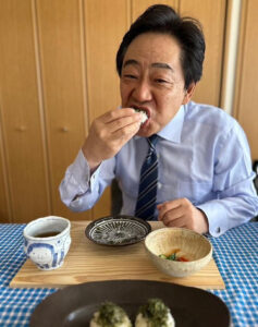 青木一彦さんがおにぎりを食べる画像