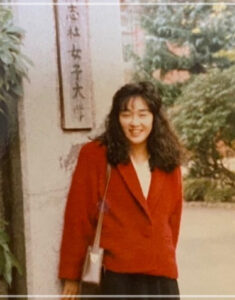 キムラ緑子さんが赤のジャケットを着て入学式で学校の校門で記念写真をしている画像